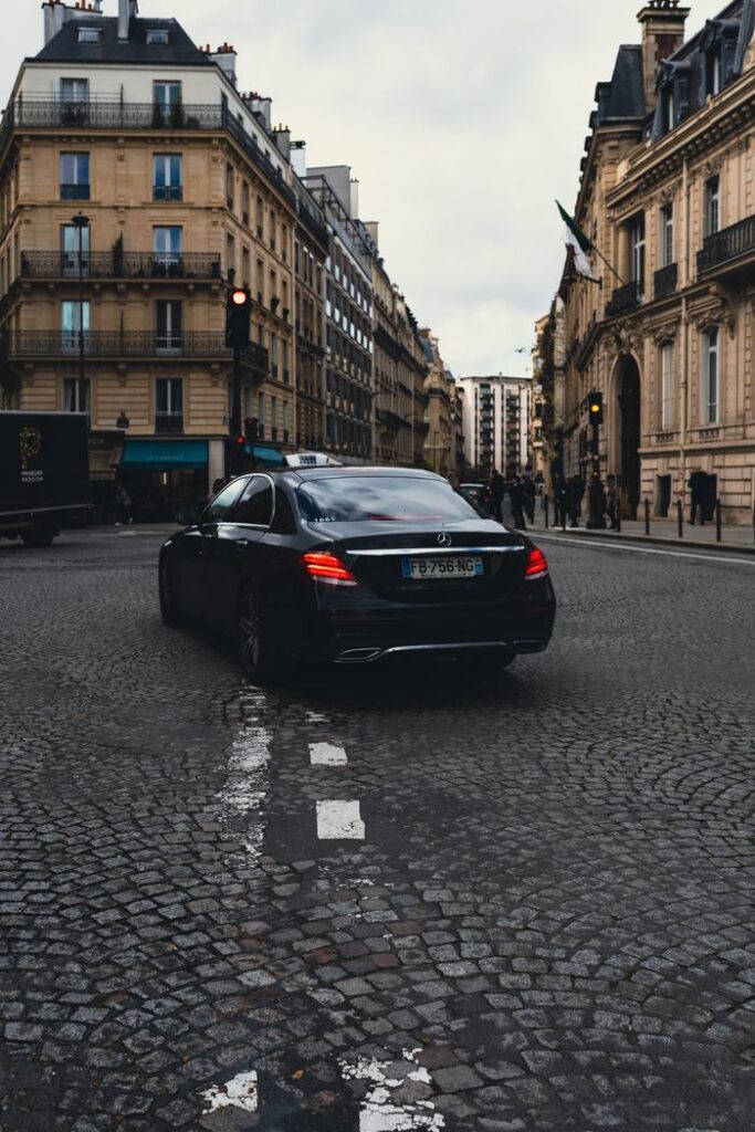 pexels photo 20810328 A black Mercedes-Benz taxi driving on a cobblestone street in Paris, surrounded by classic architecture.
